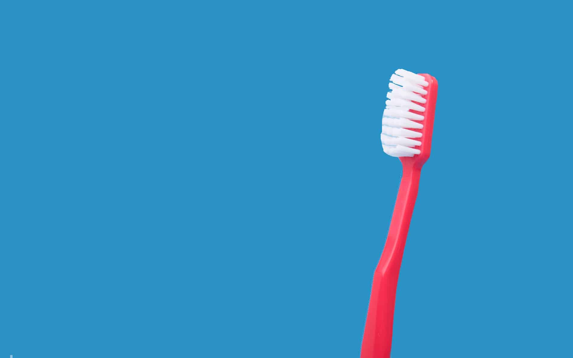 Cepillo de dientes en fondo azul.
