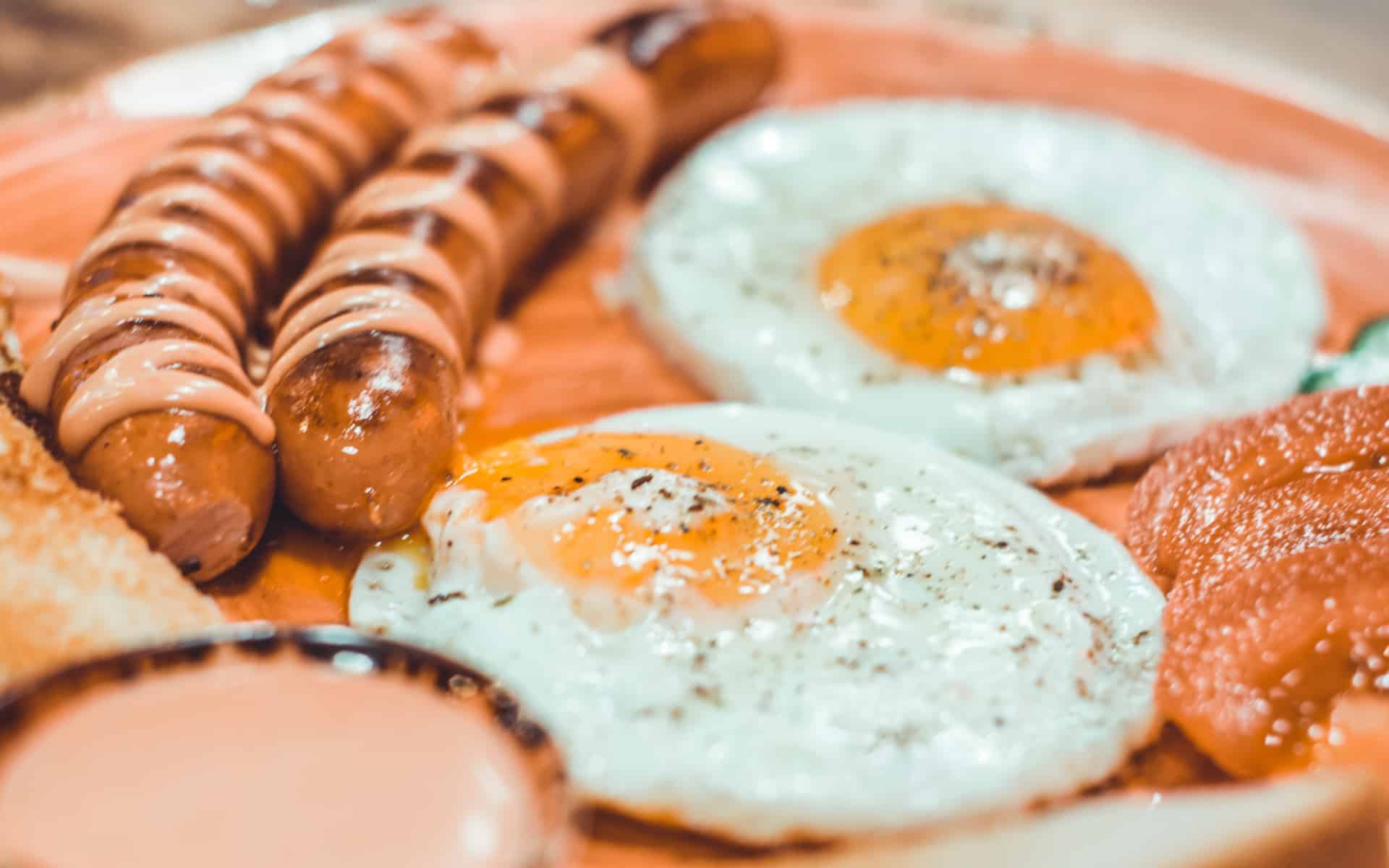 Huevos estrellados con dos salchichas al lado.