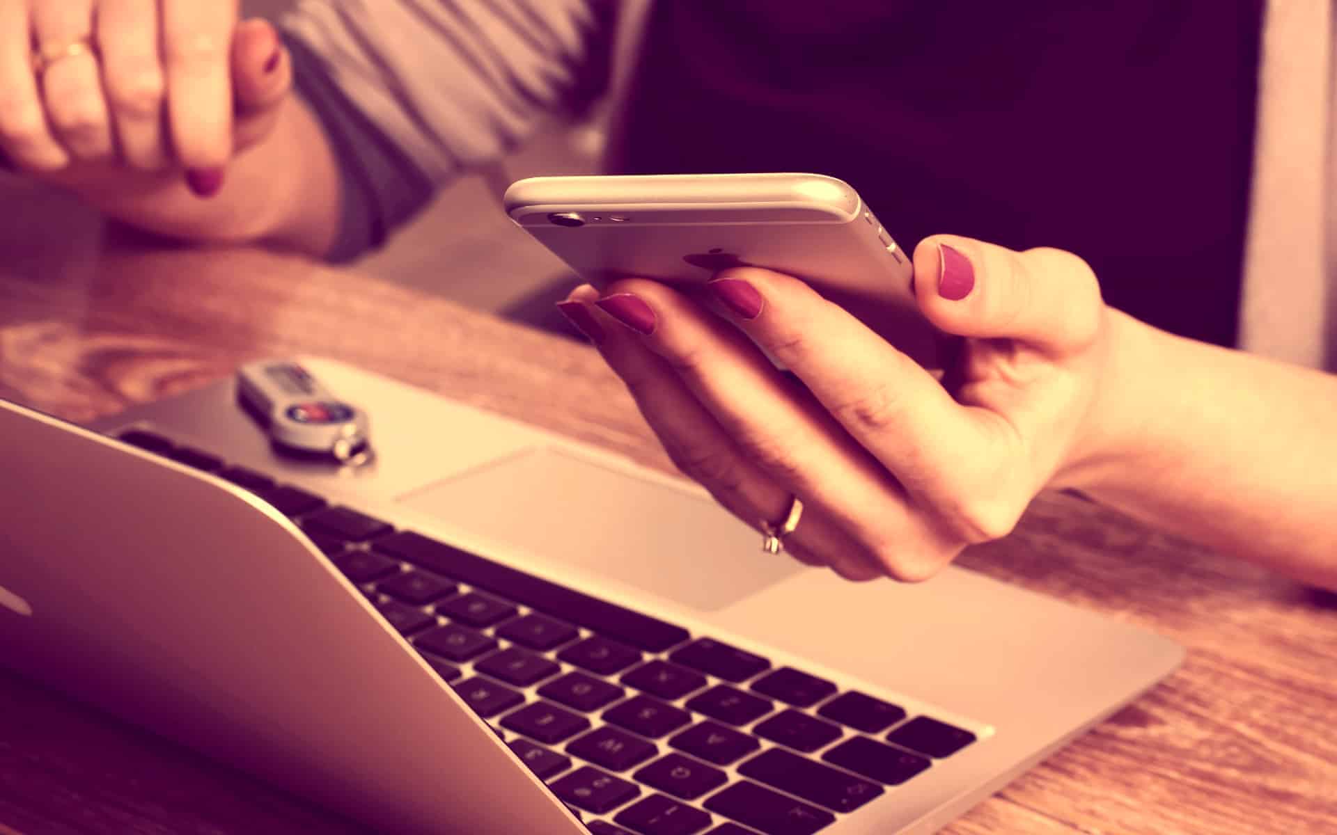 Una mujer atiende el teléfono, frente a su laptop.