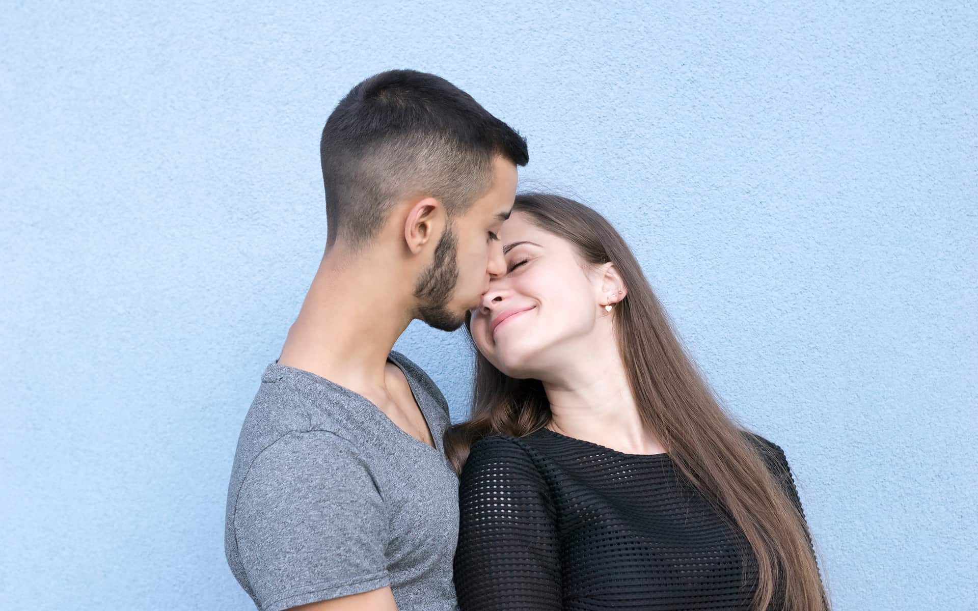 pareja dandose un beso en fondo azul